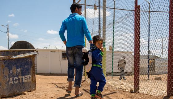 Caretaker teenager with little boy walking in a refugee camp in Jordan_180422.jpg